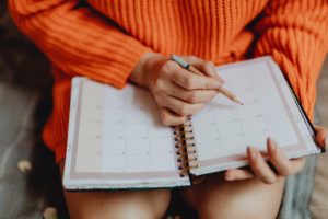 person writing in a planner to get structure 