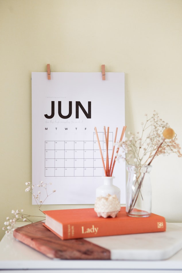 June Calendar Leaning on Desk with flowers and books