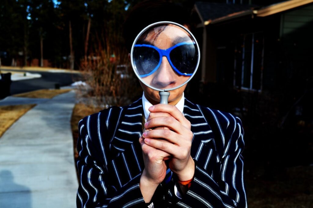 man holding magnifying glass with blue sunglasses on