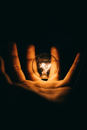 hand holding a lit light bulb