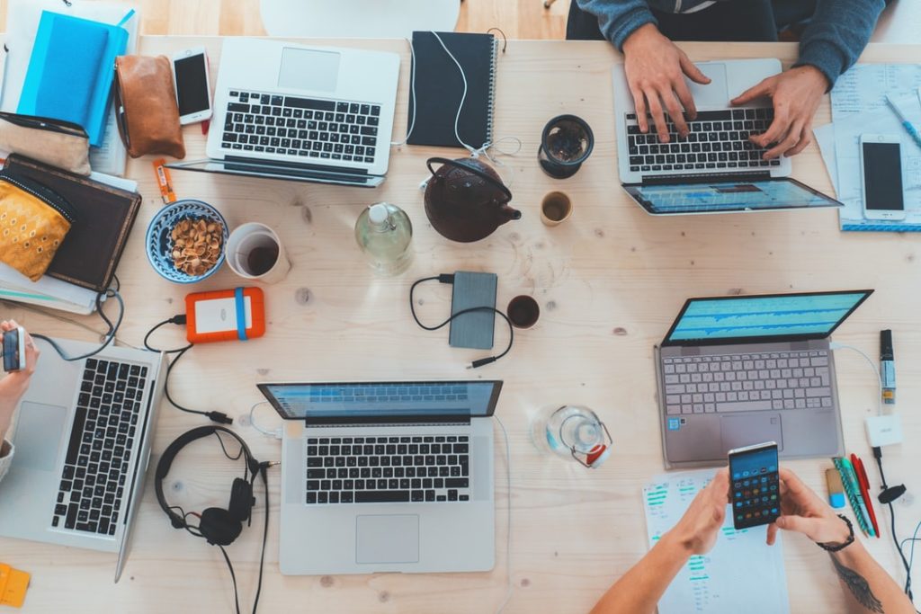 ariel shot of people working at desk on laptops 