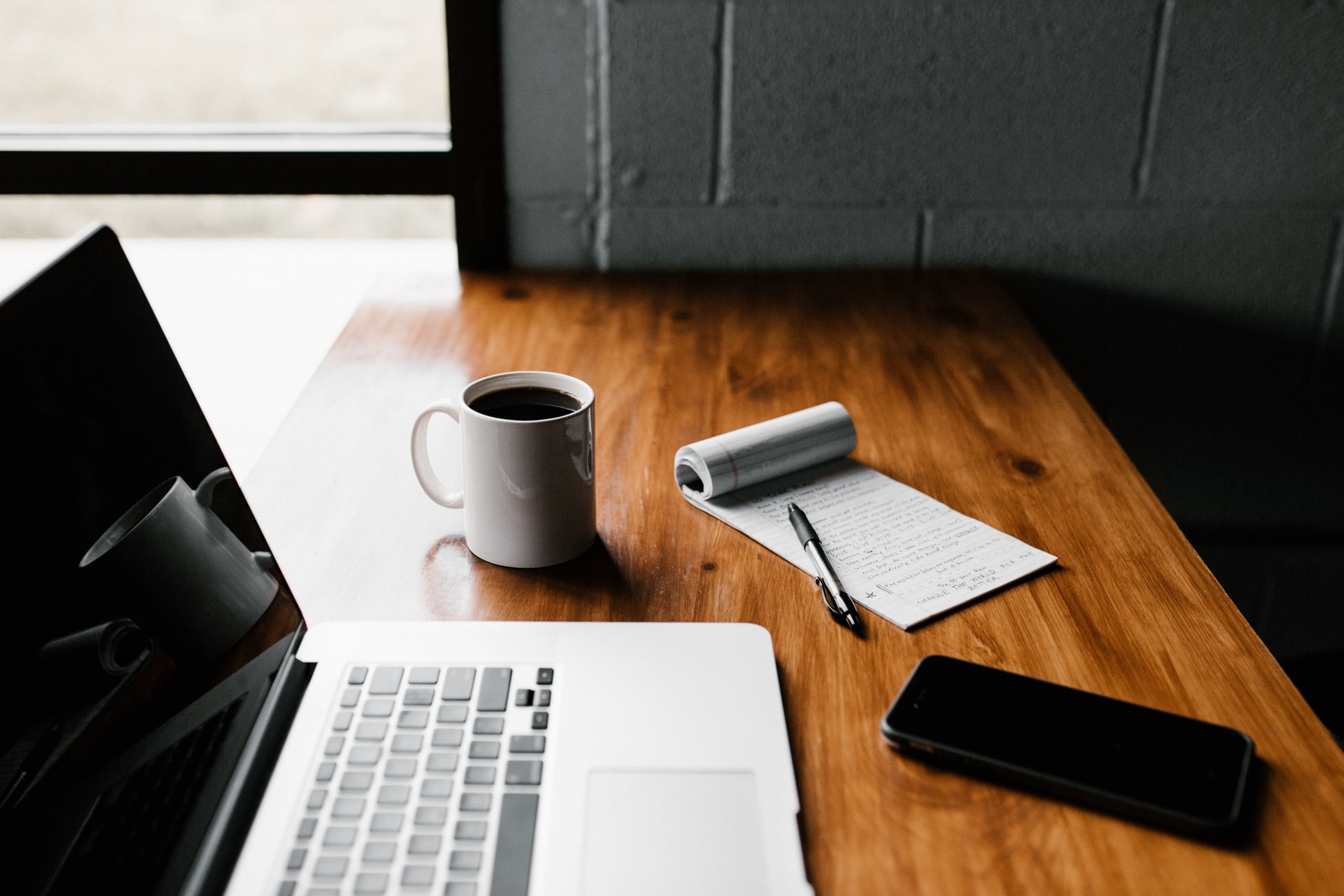 coffe mug pen and laptop on wood desk 