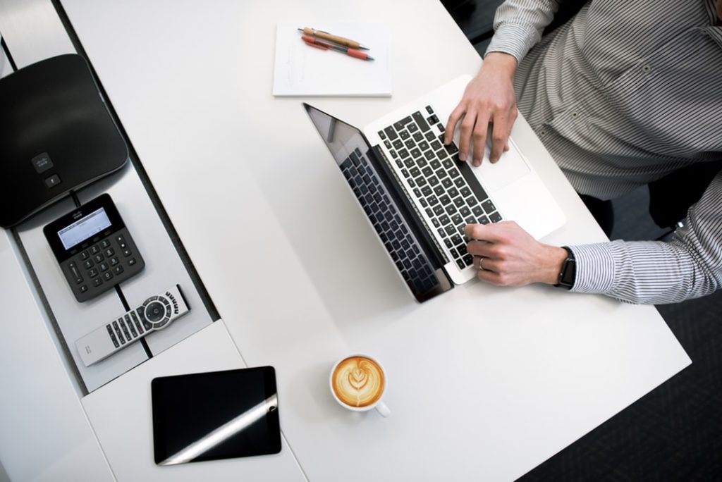 man sitting at desk, working on laptop