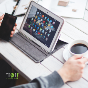 Digital Marketing | A Hand Holding A Phone and a Cup of Coffee In Front Of An iPad Sitting Infront Of a Table